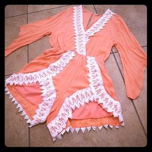 A coral orange ish romper with lace like trimming.